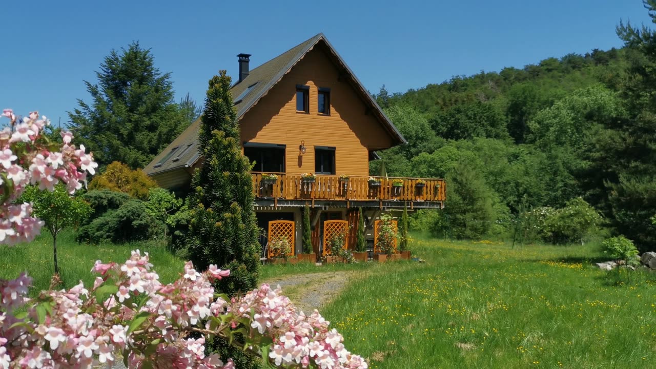 Le chalet en bois entouré de fleurs et de verdure au cœur du Massif du Sancy